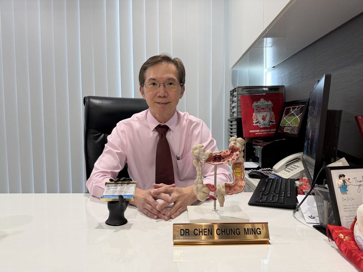 Dr Chen Chung Ming at his consultation room desk with an anatomical model of the large bowel.